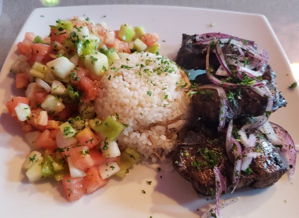 a plate with tomato salad, white rice, and lamb